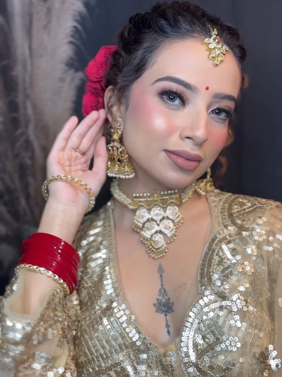 Close-up bridal makeup with dewy skin, soft blushed cheeks, and gold kundan jewellery on a bride in a gold sequin outfit with red bangles