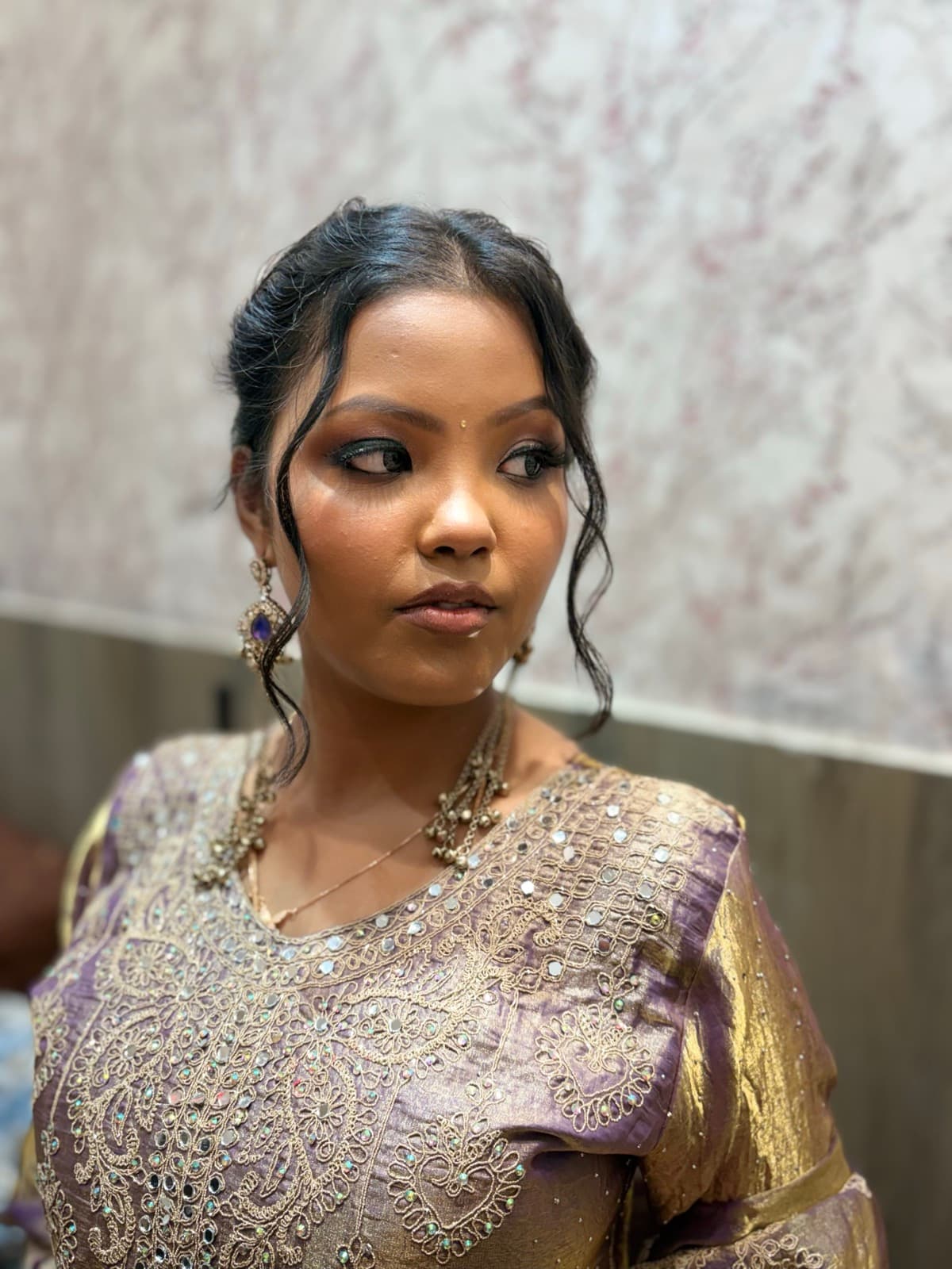 Close-up of bold eye makeup with dramatic liner and highlighted brow on a bride in a lavender lehenga