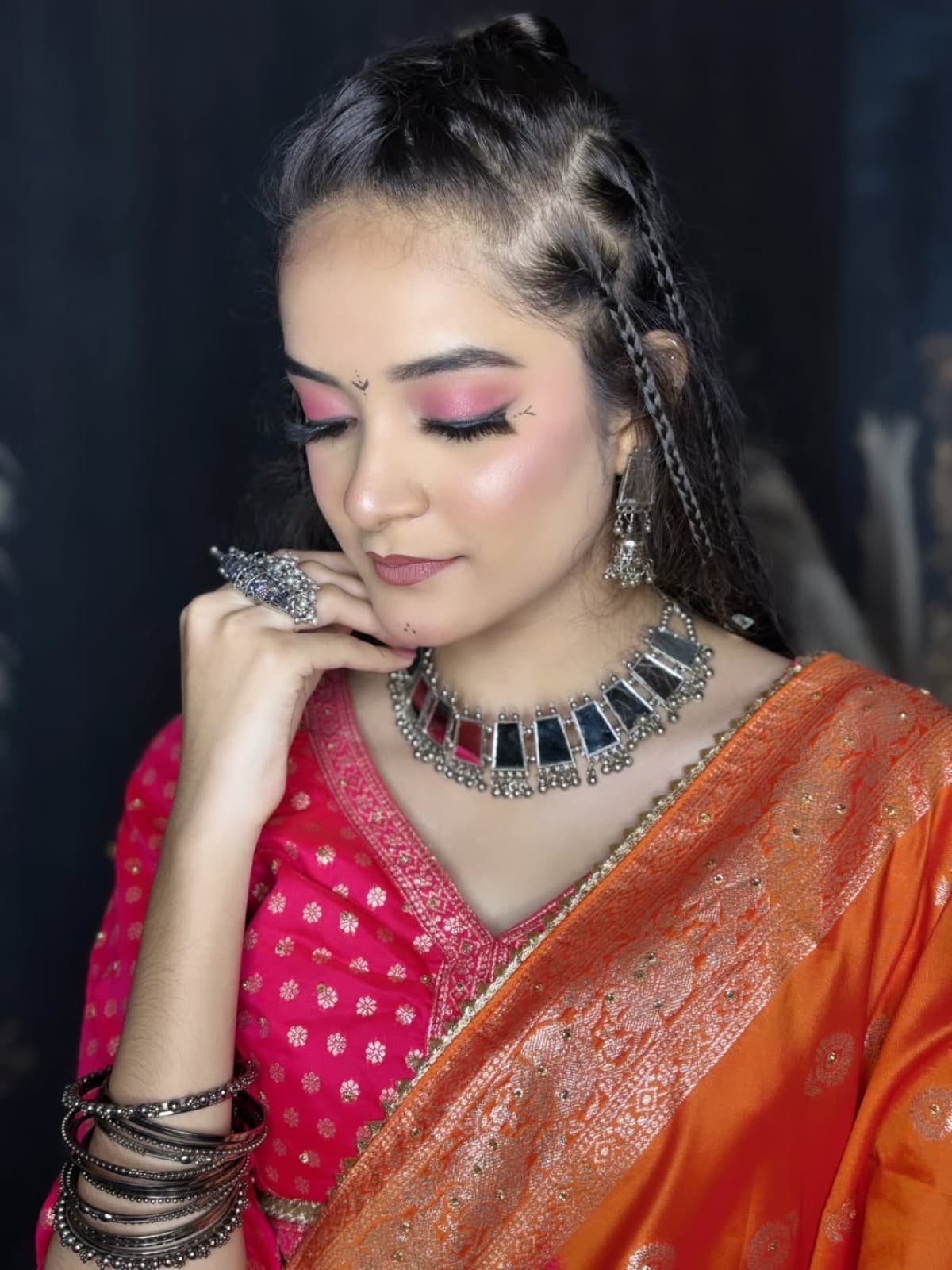 Festive garba look with pink shimmer eyes, braided hairstyle, oxidized silver jewellery, and orange banarasi dupatta over pink lehenga