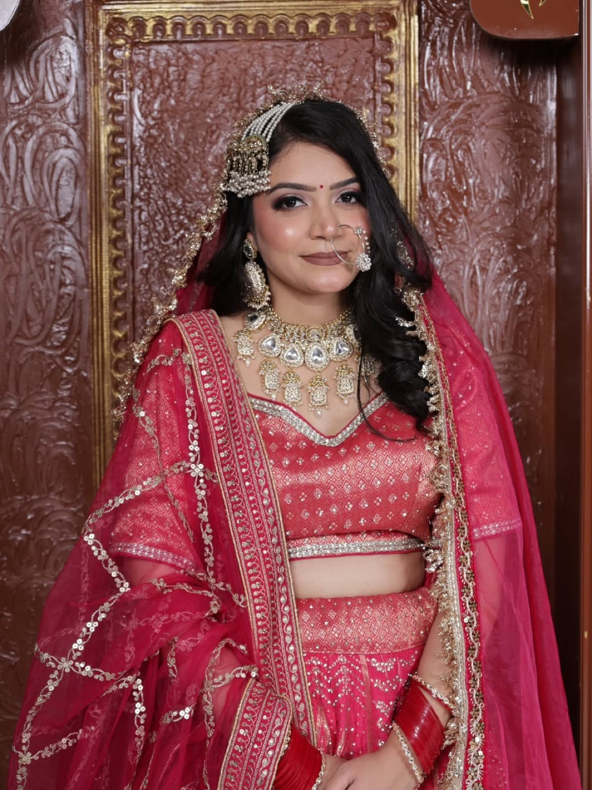 Full bridal look with traditional red lehenga, layered gold kundan jewellery, maang tikka, and nath, classic North Indian bride