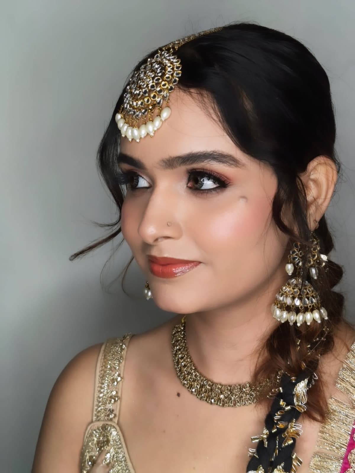Bridal makeup close-up with warm brown eyes, defined brows, and gold kundan jewellery on a bride in champagne lehenga, side profile